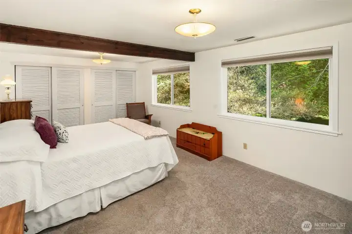 Main bedroom on main level is generous and light-filled with views of the grounds to the east.