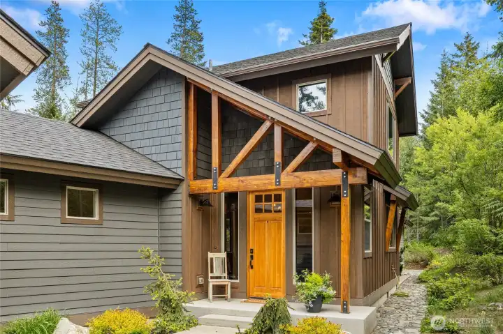 An entry framed by wood posts and beams with iron accents enhances the home’s curb appeal, blending rustic warmth with refined mountain character.