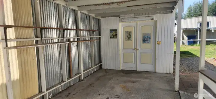 Dedicated carport provides covered parking. These doors open to the first of 2 sheds and a workshop/hobby space. Dedicated carport provides covered parking. These doors open to the first of 2 sheds and a workshop/hobby space.