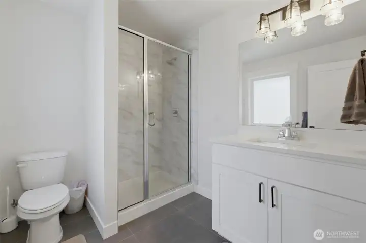 The guest en-suite bathroom has a walk-in shower with elegant marble-look tile surround, complemented by a quartz-topped vanity and modern lighting. The guest en-suite bathroom has a walk-in shower with elegant marble-look tile surround, complemented by a quartz-topped vanity and modern lighting.