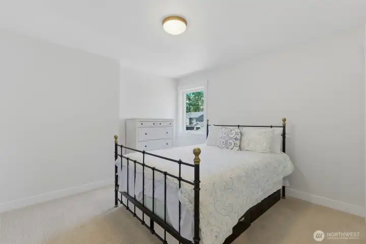 A bright, comfortably sized bedroom with carpet flooring and a peaceful window view. A bright, comfortably sized bedroom with carpet flooring and a peaceful window view.