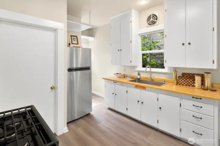 Freshly updated with new appliances, sink, faucet, flooring, and freshly refinished cabinetry, the kitchen is ready for its next owners.