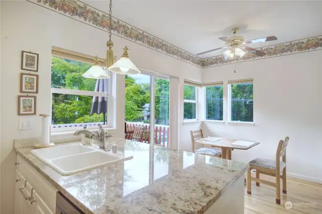 View of kitchen, nook and greenery off the deck. Fan over nook area.