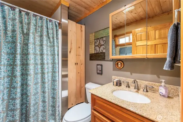 Convenient Main Floor Bathroom    Located just across from the primary bedroom, this full bathroom offers a single vanity, medicine cabinet, toilet, linen storage, and a walk-in shower.