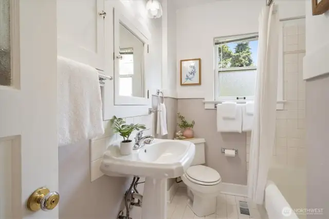 The main floor bathroom has a wonderful tub and storage tucked in behind the door.