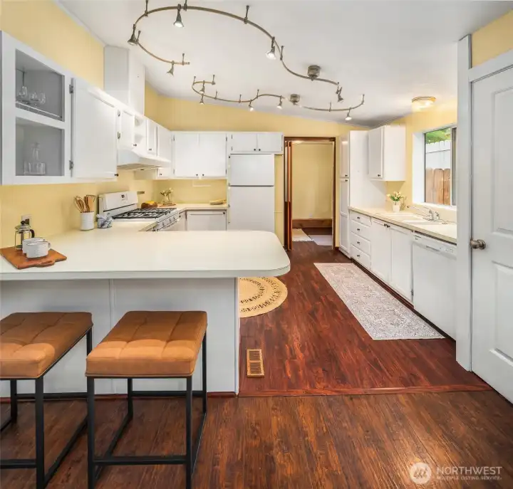 Tons of cabinetry and countertop space in this very functional kitchen. Pantry behind door on right; laundry room/mud entry through far door.