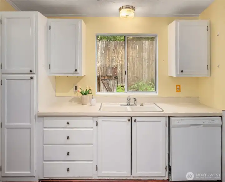 Kitchen window looks out onto the partially fenced, paved patio area on the south side of the home. Lots of storage in this kitchen!