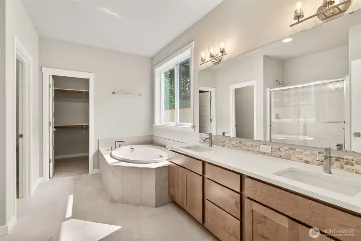 5-piece primary bath with tile floors, quartz counter, dual vanity sink and soaking tub.