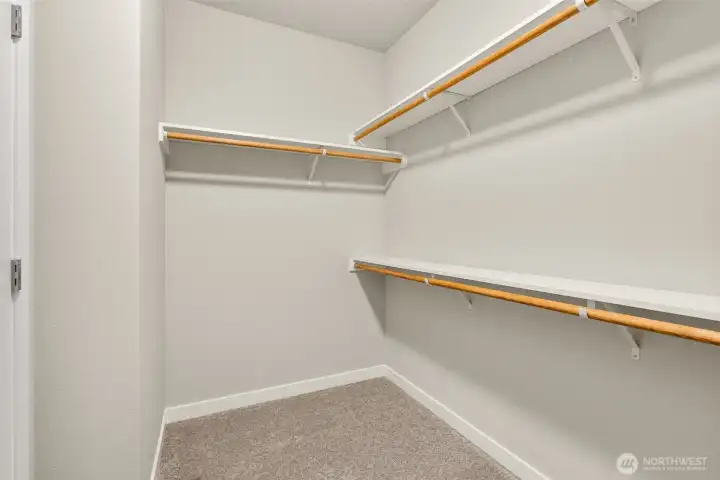 Primary walk-in closet with solid shelving.