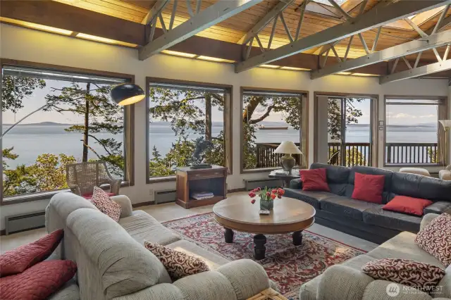 Large picture windows reveal stunning west-facing water views. A sliding door leads out to the view deck above the water.