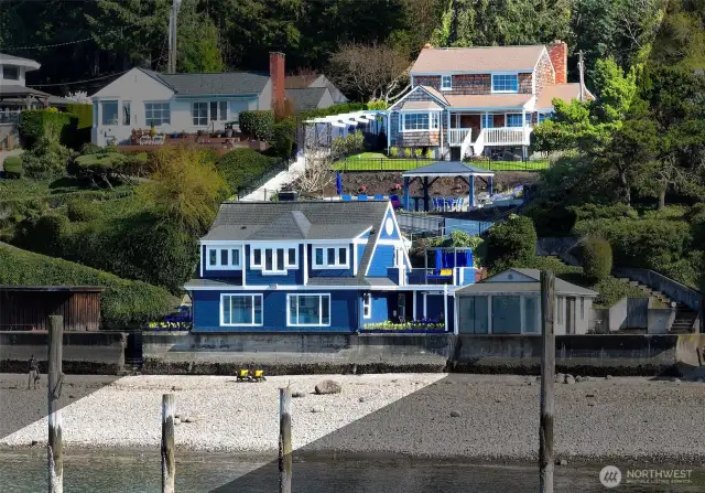 From Puget Sound to treetops, the full Caledonia Cove estate unfolds. At water’s edge, the Beach House and Boat House of 7316 Eastside Drive NE welcome the tides. Mid-slope, the Coach House offers utility and versatility. Above it all, the Cape Cod residence at 7314 crowns the hillside with commanding views. Together, the two addresses span a private, multi-tiered retreat from street to shore.