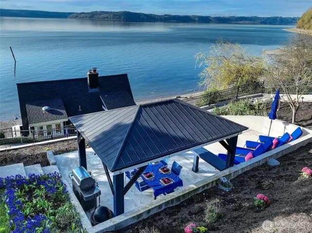 Steps from the sand, this waterfront terrace at 7316 Eastside Drive NE sets the stage for unforgettable meals. Nestled beside the Beach House and framed by coastal blooms, the open-air dining area offers seamless connection to the Sound. Casual elegance, tidepool-side.