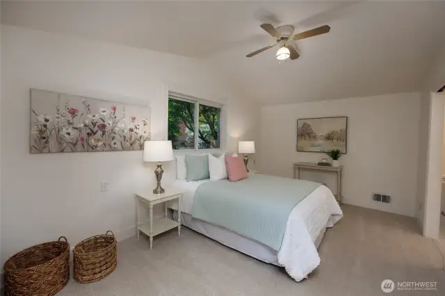Primary suite with vaulted ceilings, ceiling fan, remodeled en-suite bath and walk in closet.