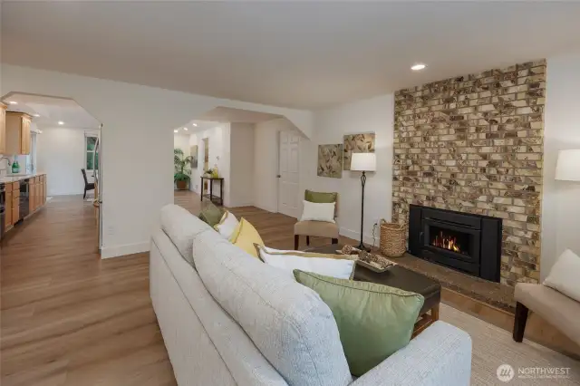 Sunny living room with wood burning fireplace, all new vinyl plank flooring and interior paint.