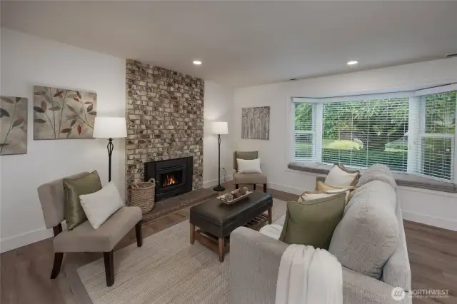 Sunny living room with wood burning fireplace, all new vinyl plank flooring, interior paint plus newer windows and blinds throughout.