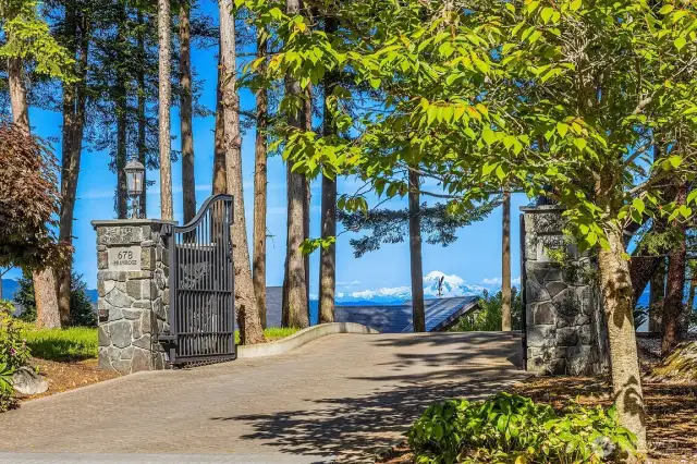 Steel double front entry gate is hand-made with an inlayed eagle in flight, supported by  columns of Lynch Creek stone, opening to a 900’ lighted driveway of Belgian block  concrete pavers and garden blocks.