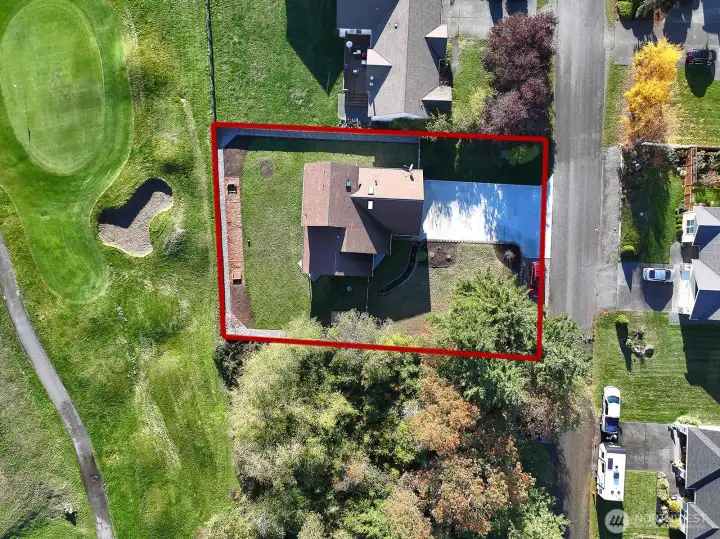 Drone shot of the home, approximate property lines and location near lovely trees and the golf course.