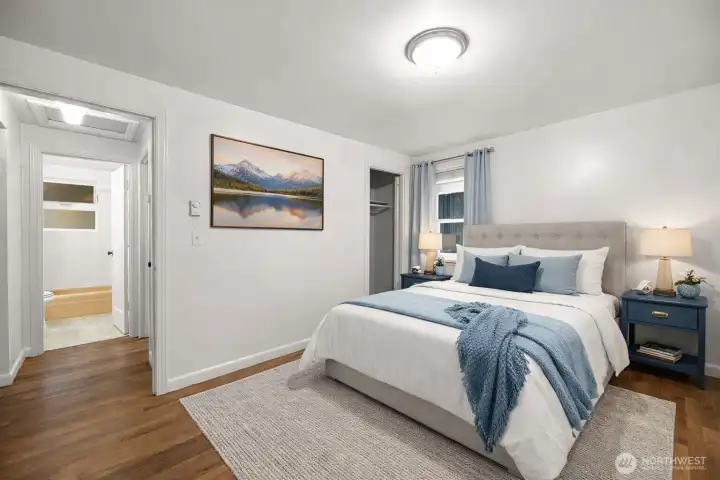Comfortable primary bedroom with good natural light and hardwood floors. This photo is virtually staged