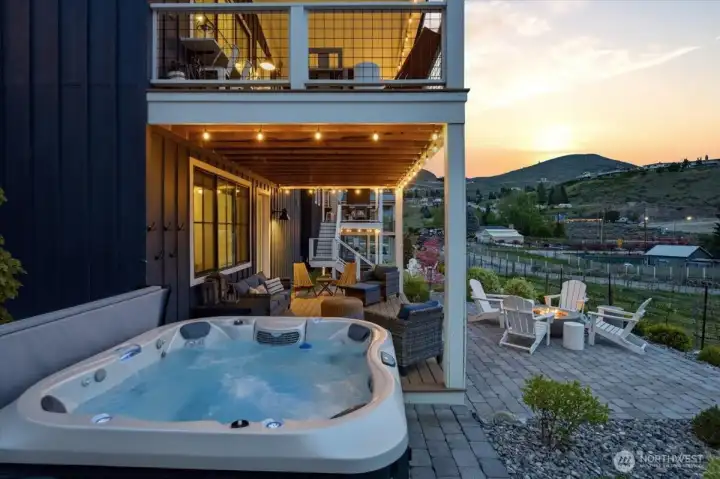 Twilight view of outdoor living area with private hot tub, deck, patio and custom fire pit overlooking the Vin du Lac vineyards.