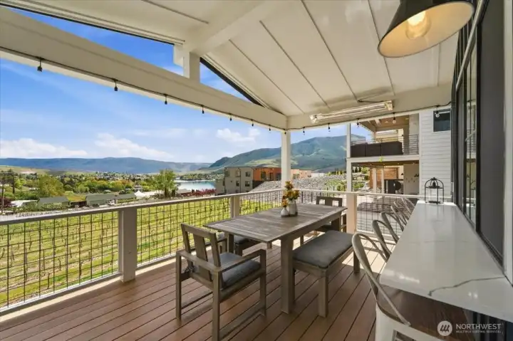 Main level outdoor living area with sit up bar with quartz countertops, dining table and views overlooking the Vin du Lac vineyards.