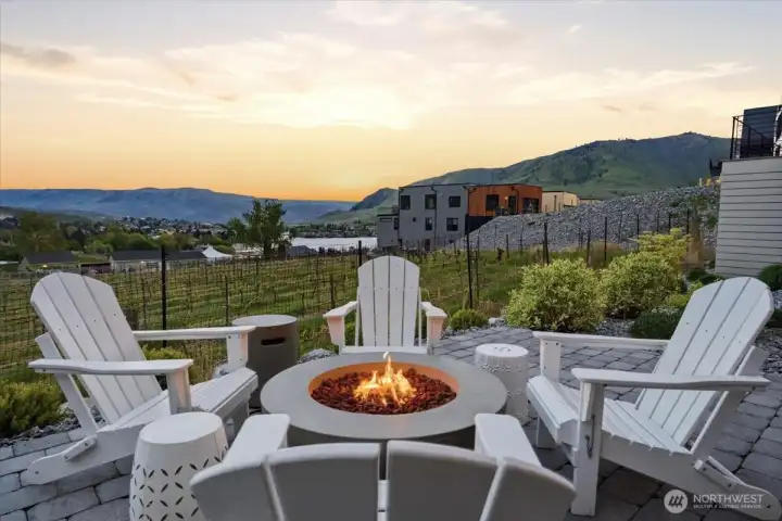 Twilight view of outdoor living area with custom fire pit and Adirondack chairs overlooking the Vin du Lac vineyards.