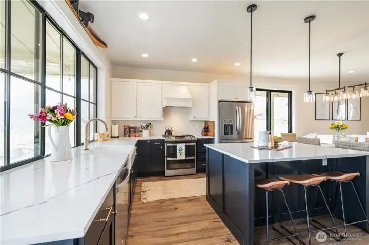 Kitchen with quartz countertops, engineered wood flooring, stainless steel appliances, sit up bar and French doors leaded to the view balcony and outdoor living space with BBQ and dining and lounge areas.
