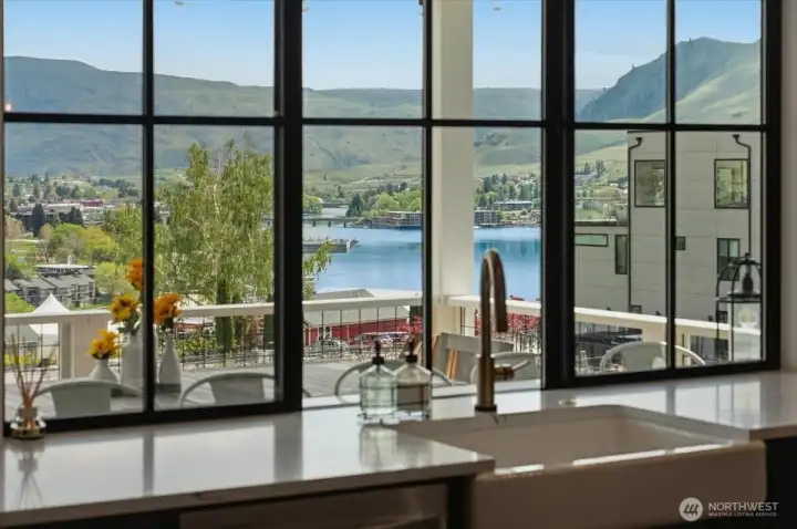 Detail view of kitchen with quartz countertops, farmhouse sink and upgraded black trimmed windows overlooking the lake and vineyard view deck and outdoor living area.