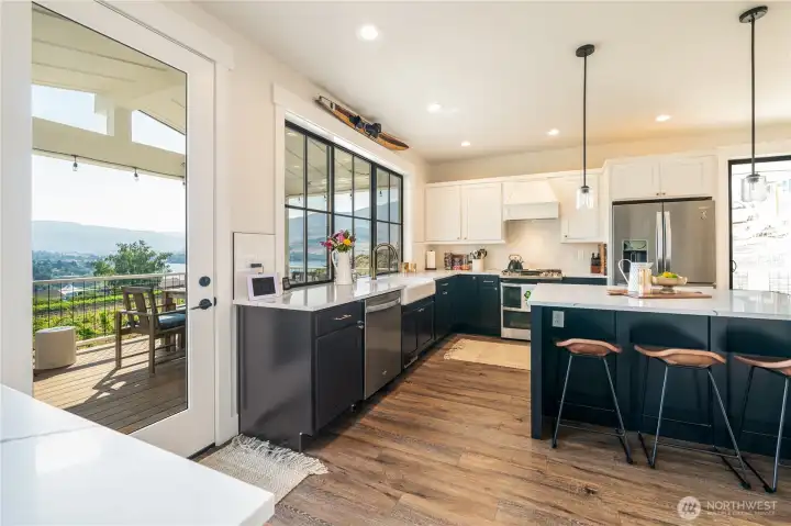 Kitchen with quartz countertops, engineered wood flooring, stainless steel appliances and French doors leaded to the view balcony and outdoor living space with BBQ and dining and lounge areas.
