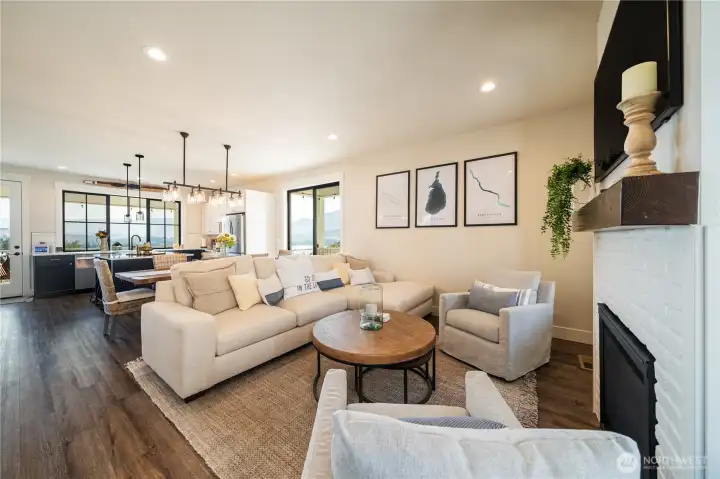 View of living room with double sided fireplace looking towards the dining room and kitchen.