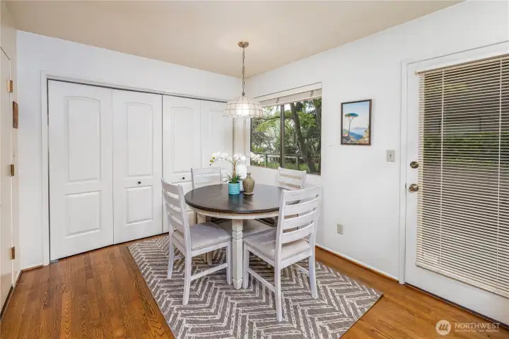 The bright and functional breakfast nook offers a cozy spot for everyday dining, with large windows bringing in natural light and easy access to the side yard. A wall of discreet closet doors provides abundant storage, thoughtfully concealing a pantry and full-size washer and dryer for added convenience.