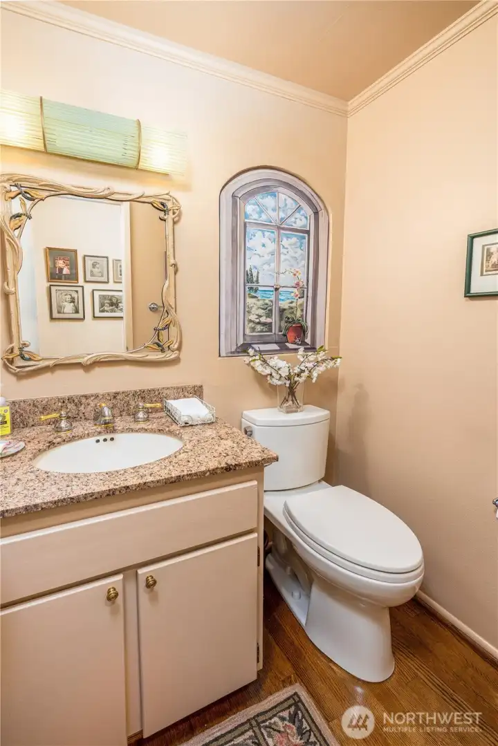 The half bath on the main floor features hardwoods and granite counter.