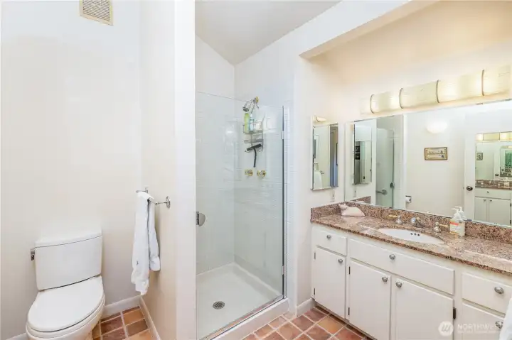 Three-quarter primary bath with glass shower and ceramic tile flooring.