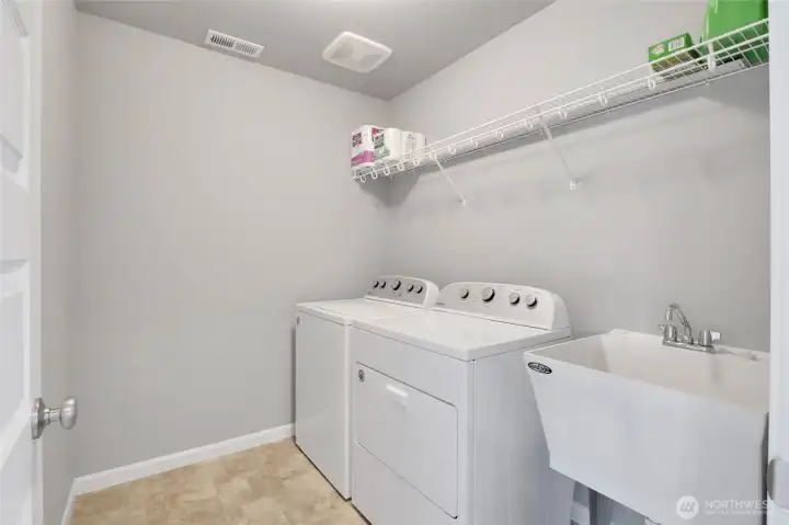 Dedicated laundry room with utility sink and shelving.