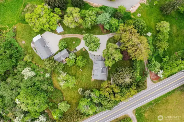 Home is beautifully situated on the site. This view shows the home to the right with circular drive, smaller carriage house and four-car garage to left.