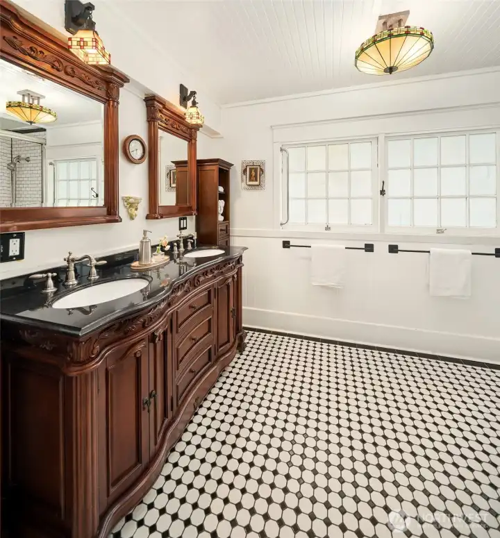 Primary bath with custom tiled floor and bath surround. Period windows and light fixtures complement the home's style.