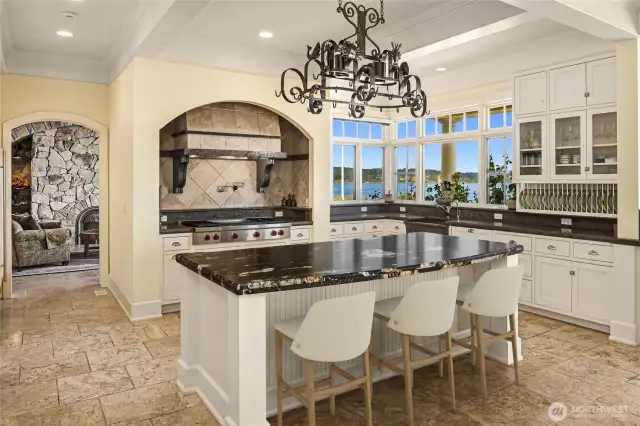The kitchen blends form and function, featuring tuxedo limestone countertops honed to reveal the stone’s natural beauty. The timeless white cabinetry with seeded beach glass inserts adds a touch of coastal charm, while commercial-grade appliances ensure the kitchen is ready for any culinary challenge.