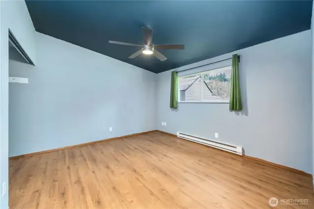 This spacious secondary bedroom features updated flooring, fresh paint, and a ceiling fan for added comfort. The large window brings in beautiful natural light and frames peaceful outdoor views, making it ideal for a guest room, home office, or creative space.