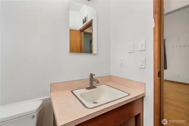 A closer look at the bathroom’s vanity highlights the upgraded faucet, large mirror, and retro countertop—offering charm and function in one. Convenient electrical access nearby makes daily routines a breeze.