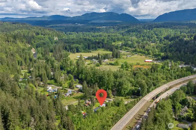 Surrounded by natural beauty! Aerial view shows proximity to Cedar River, quiet roads, and scenic forested backdrop.