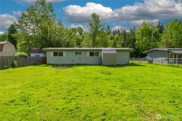 Back exterior with fresh lawn, storage shed, and large windows—ready for outdoor living and enjoying the fresh air.