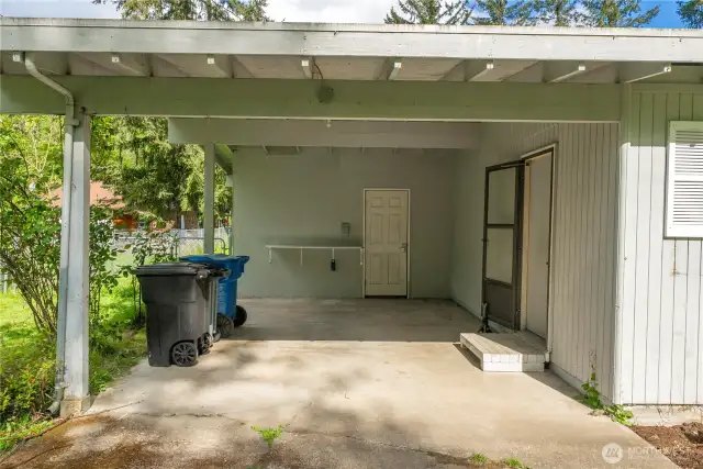 Covered carport leads directly to the home entrance and utility area, offering protection from the elements and added storage options.