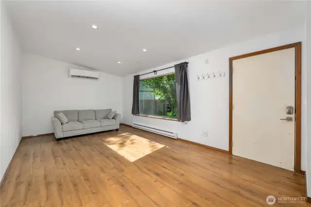 This inviting living space features warm wood-style flooring, recessed lighting, and a large picture window that fills the room with natural light. Stay cozy year-round with a ductless mini-split for efficient heating and cooling, plus baseboard heat for added comfort. A perfect spot to relax, unwind, or entertain in a home that offers both charm and function.