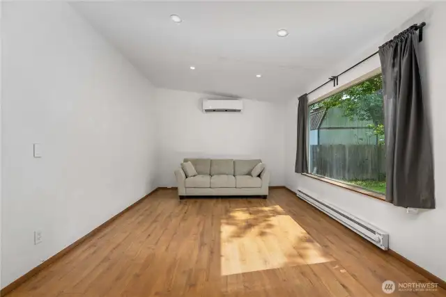 This bright living room features updated flooring, recessed lighting, and a large picture window that fills the space with natural light. Enjoy year-round comfort with the energy-efficient ductless mini-split system and baseboard heat.