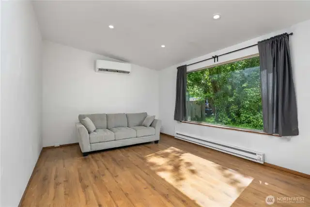The inviting living room offers durable flooring, recessed lighting, and a peaceful view of the private yard through the oversized picture window. Stay cool in the summer and warm in the winter with the ductless mini-split and baseboard heating system.