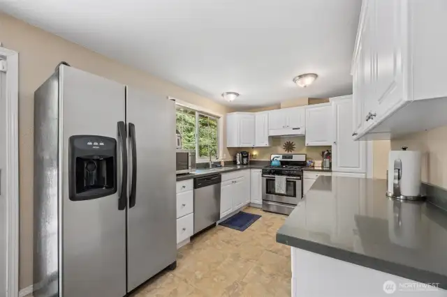 Updated kitchen featuring newer cabinets, quartz countertops and modern finishes.  Fridge, dish wahser & stove/ oven appliances all stay.
