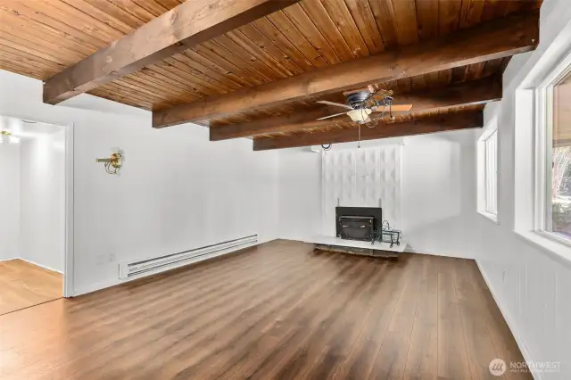 Lower level rec room with open beam ceiling and woodstove insert