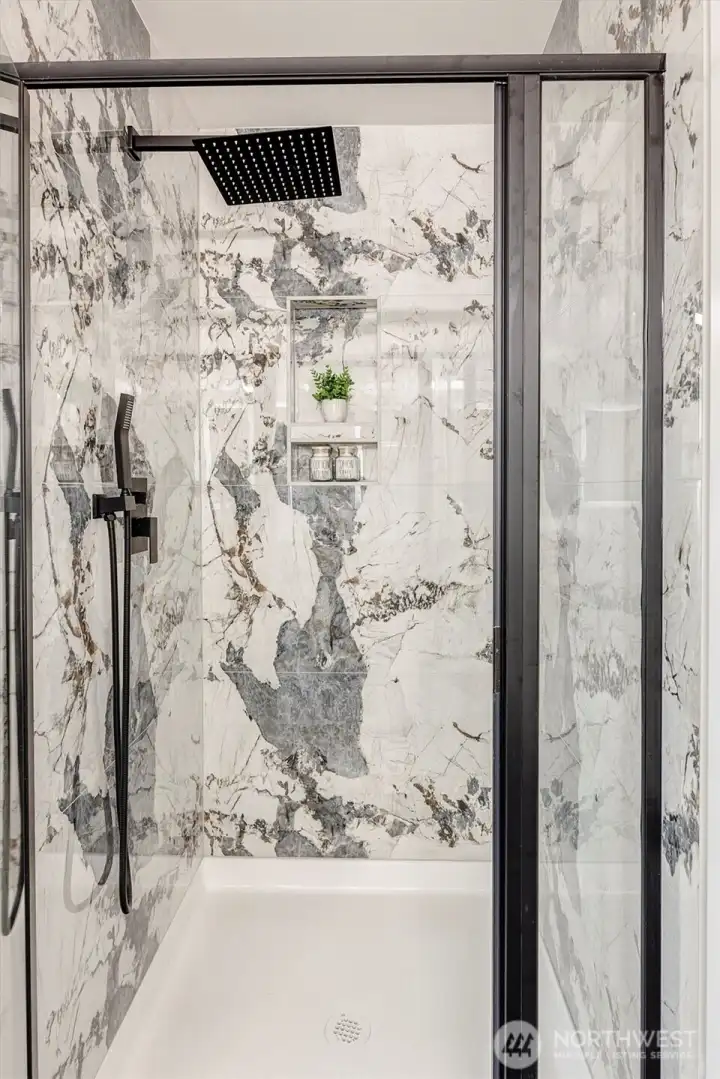 Shower in primary bath has rain head and handheld sprayer.