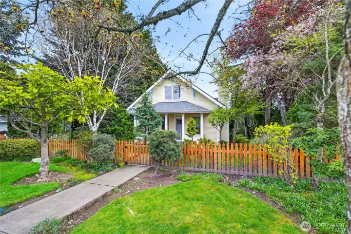 Charming in-town home with front view of main house from L Avenue, with lush landscaping and wooden picket fence