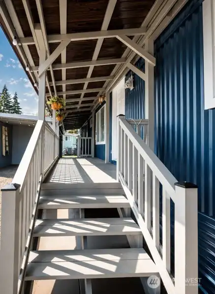 Covered side porch with sturdy wood and concrete base, blue siding, and exterior access.