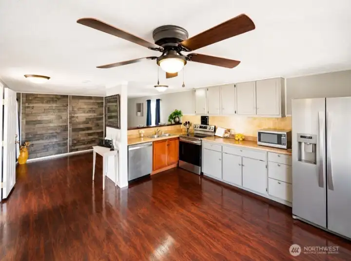 Spacious open-concept kitchen and dining area with hardwood floors, ceiling fan.